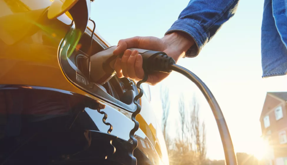 A person plugs in an electrical vehicle for charging
